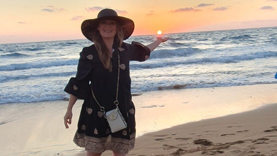 Silvia Schuldis am Strand bei Sonnenuntergang, die Sonne in ihrer Hand